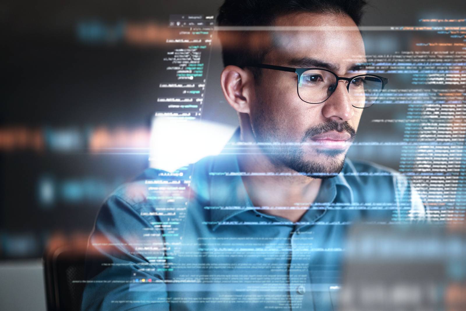 Programmer, coding and man with focus, hologram and data analytics with cyber security, futuristic and stock market. Male person, coder or programming with innovation, research or finance information A developer reviews lines of code on a transparent digital display screen